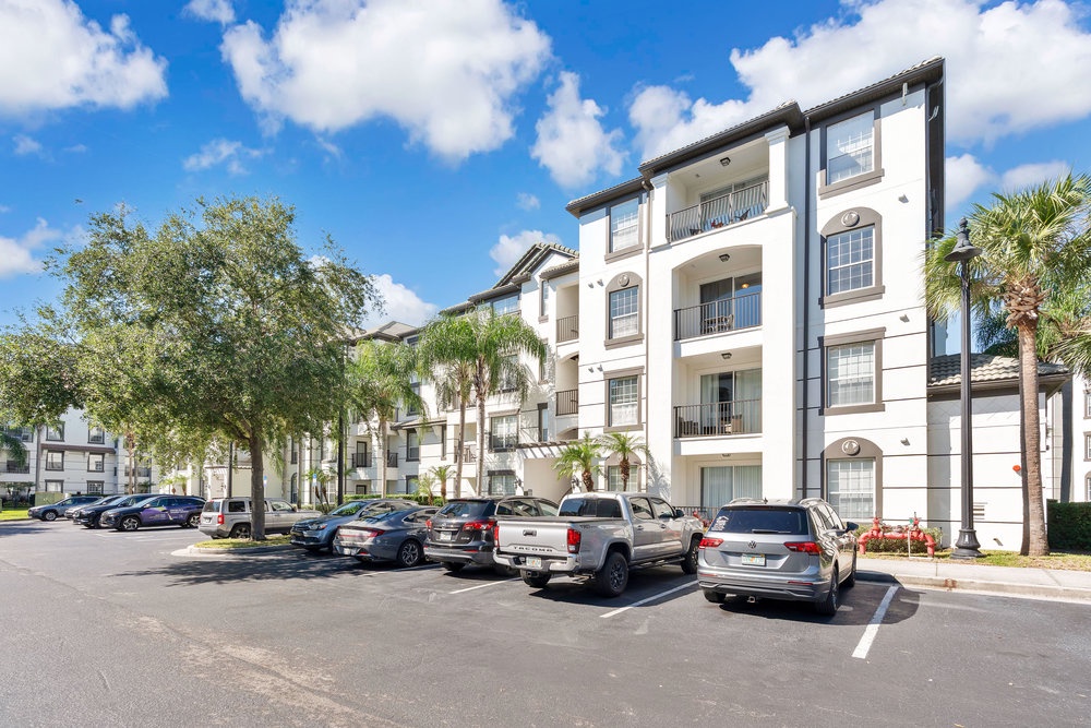 Modern multi-story residential complex with convenient parking and tropical landscaping in a peaceful community setting.