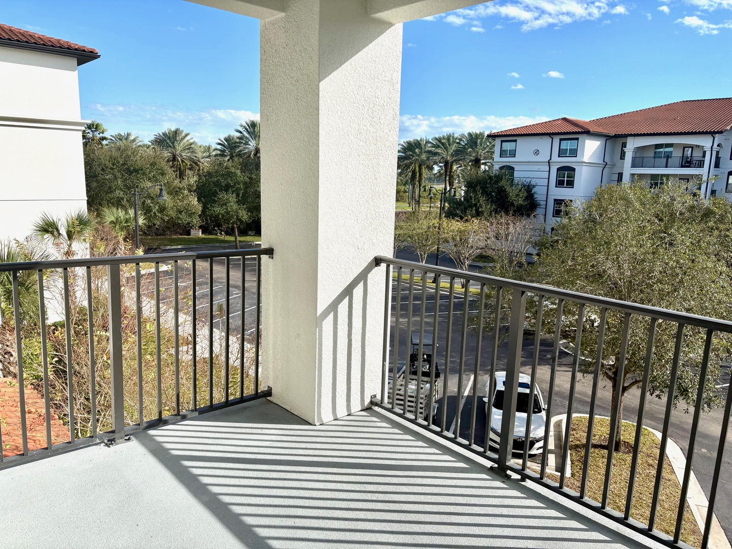 Your private balcony offers peaceful views of lush palm trees and the quiet residential area below, perfect for morning coffee moments.