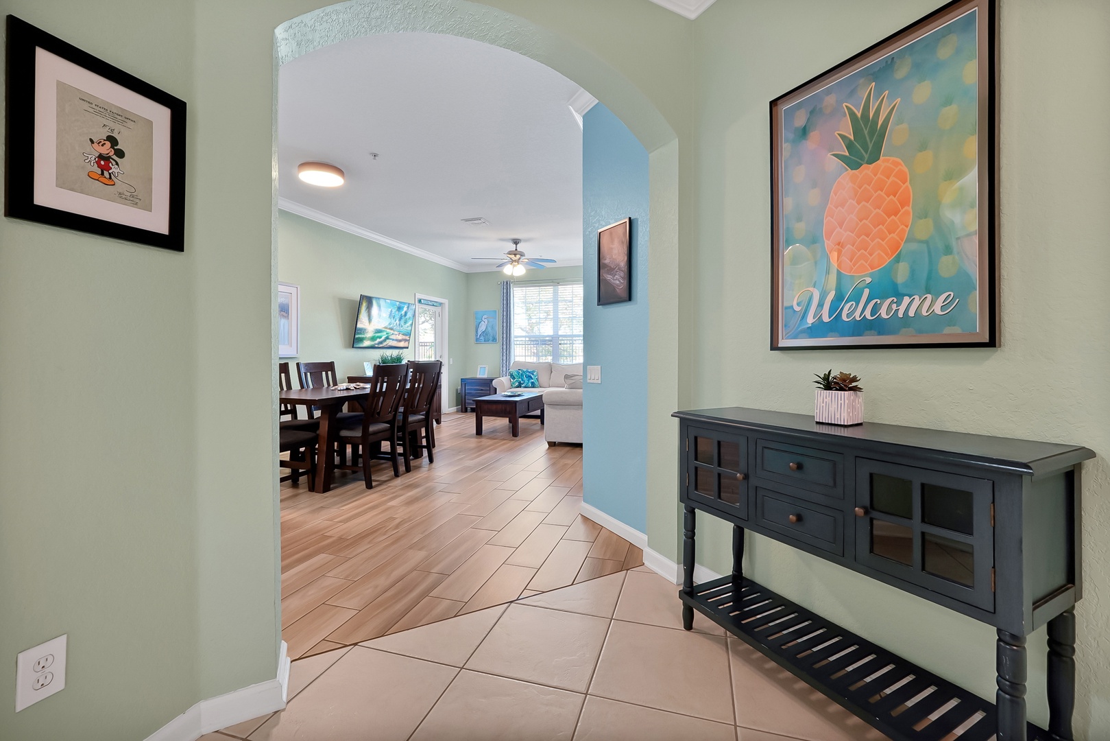 Step into your welcoming entryway where cheerful tropical artwork greets you before flowing into the spacious dining and living areas beyond.