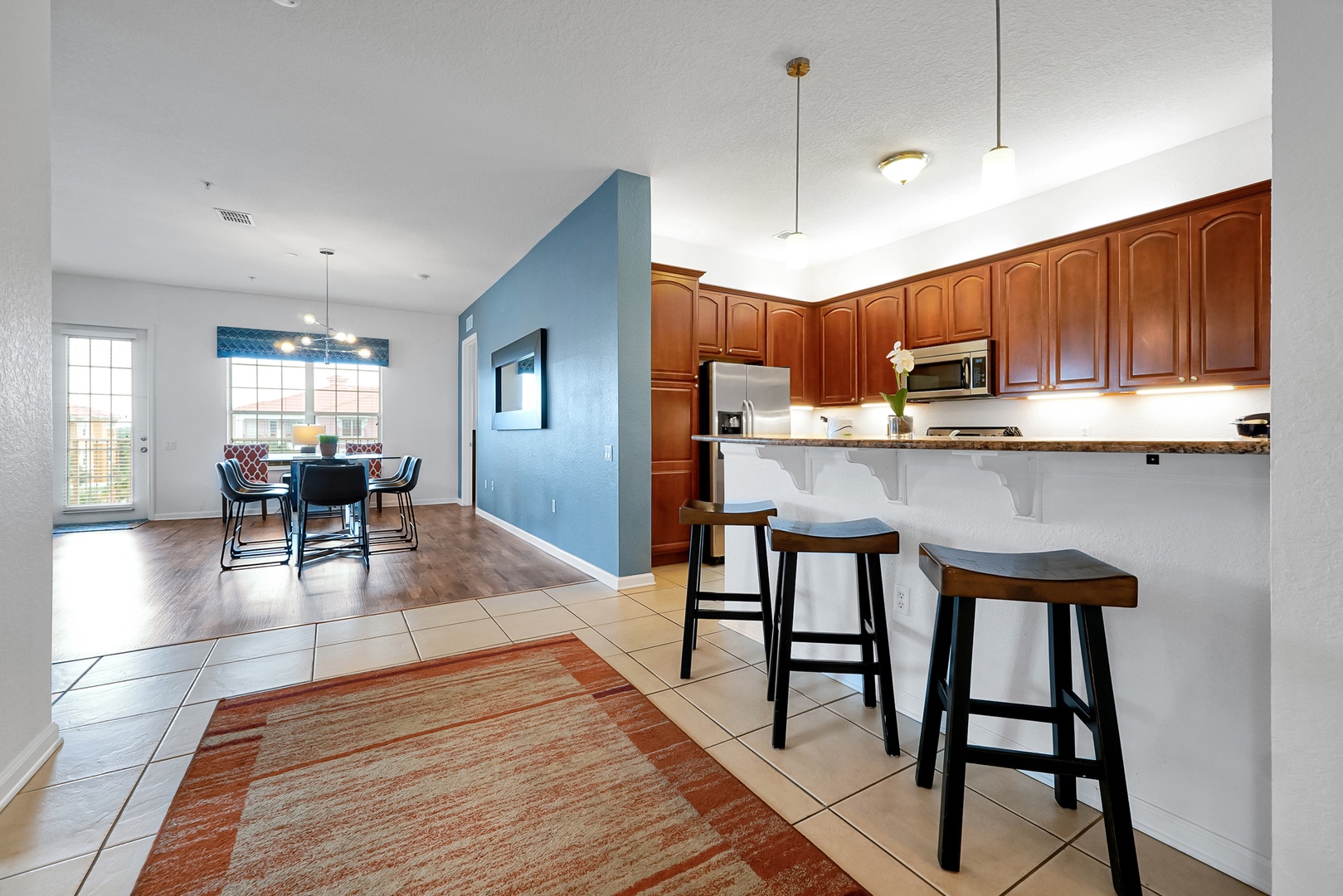 Step into your open-concept kitchen and dining space, where warm wood cabinetry meets a welcoming breakfast bar with cozy seating. Natural light streams through the dining area, inviting you to enjoy morning coffee or evening meals in comfort.