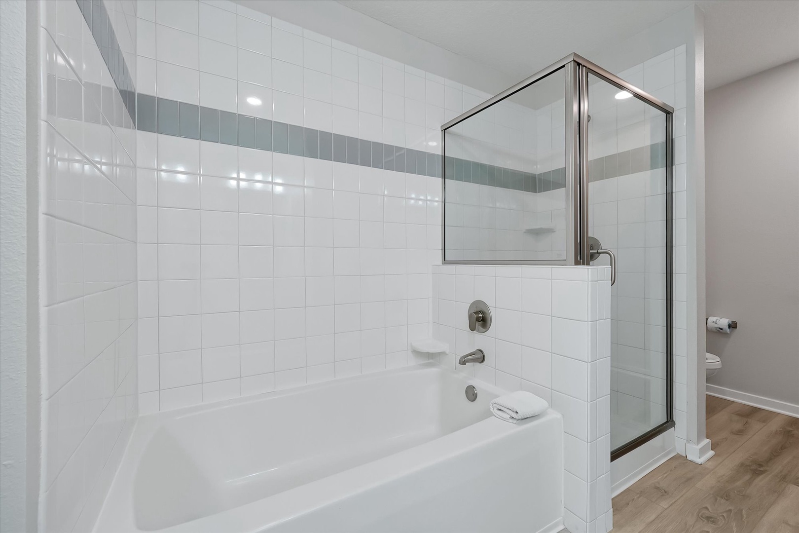 Unwind in your pristine bathroom featuring a deep soaking tub and separate glass-enclosed shower with elegant tiled walls.