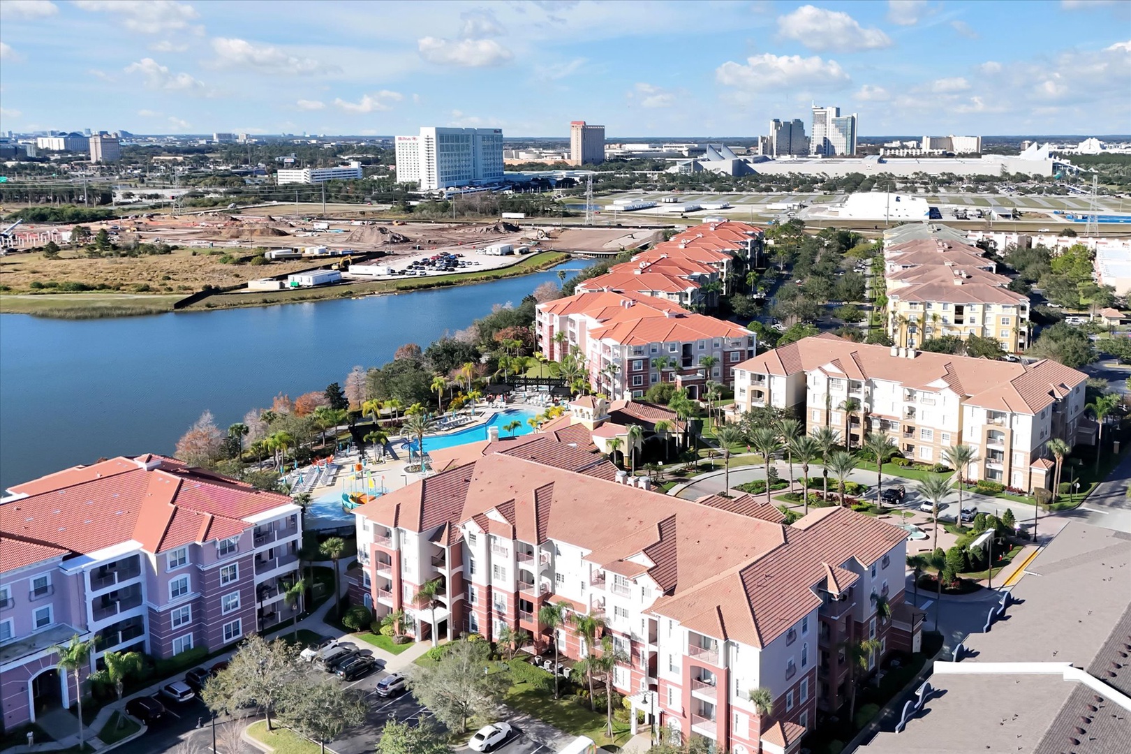 Expansive resort complex with swimming pools and lakes set against Orlando's skyline backdrop.