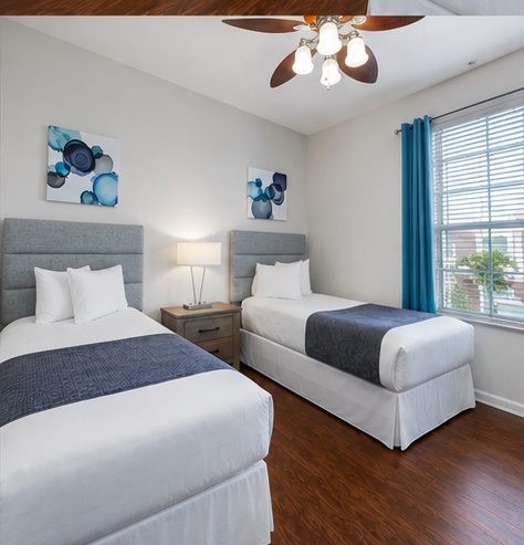 Drift off in crisp white linens while the ceiling fan gently circulates cool air through your peaceful twin bedroom retreat.