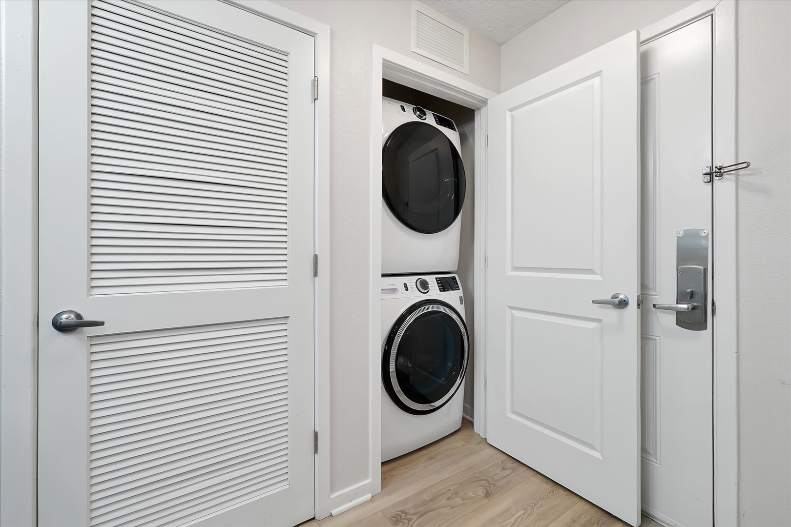 Your convenient in-unit laundry room keeps fresh clothes within reach, featuring modern stackable machines tucked neatly behind crisp white doors.