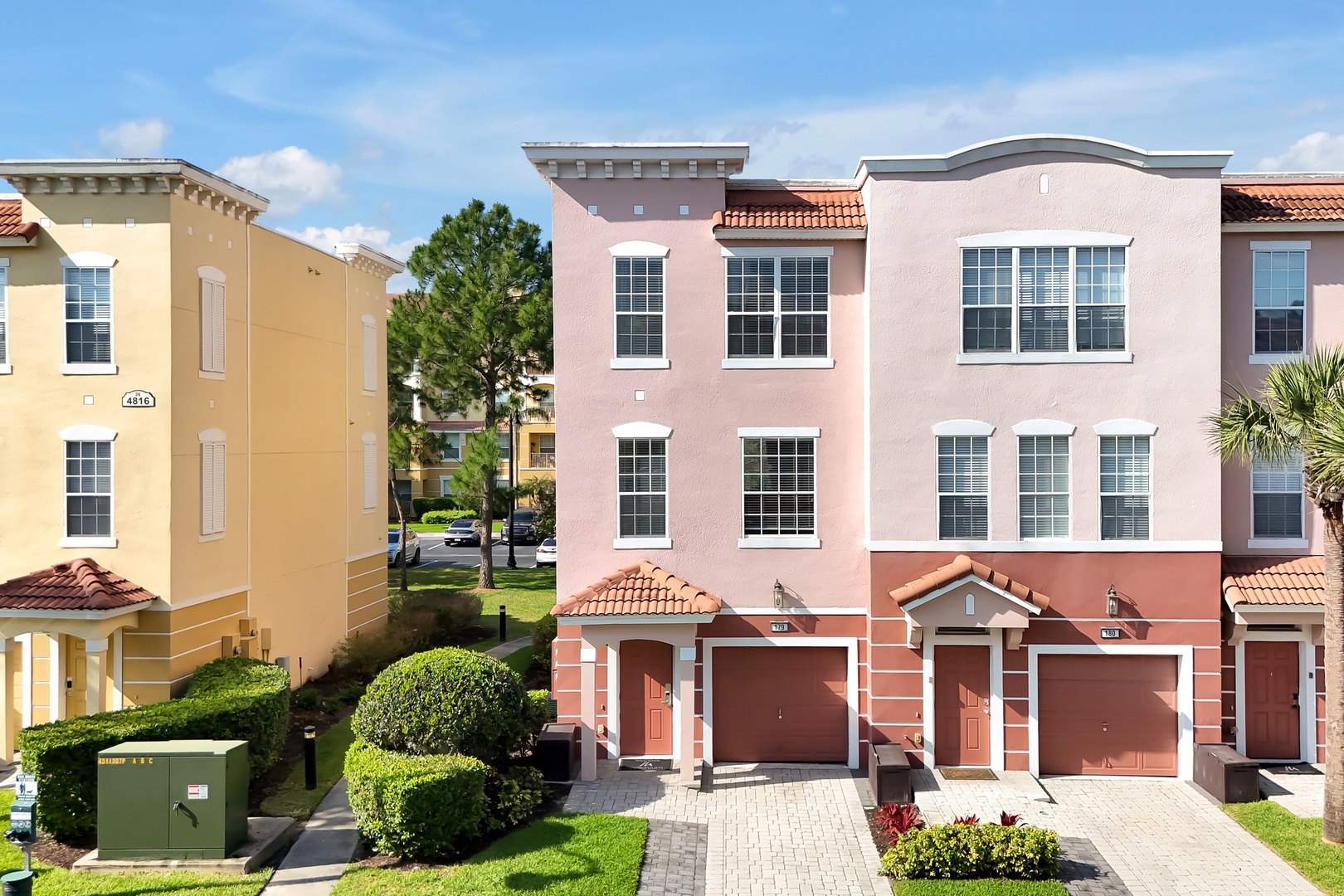 Modern townhome community with Mediterranean-style architecture featuring terracotta roofs and colorful facades in a peaceful residential setting.