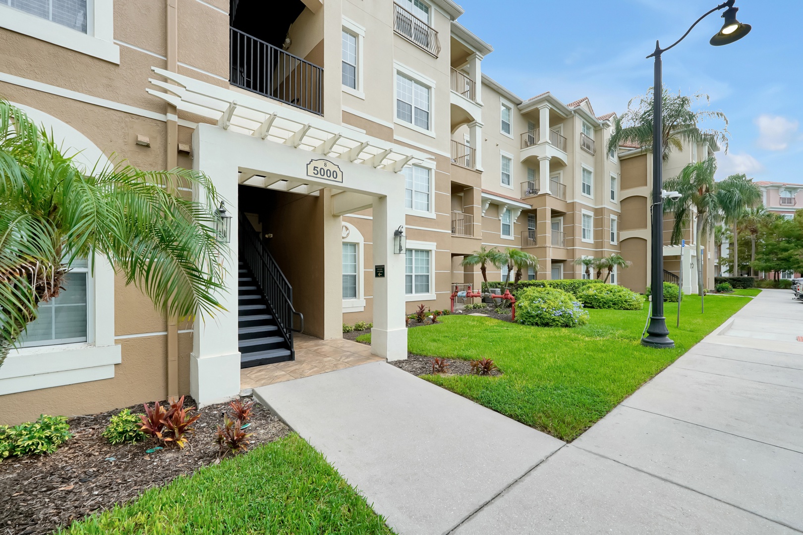 Located in the building 5000, right nThe property features a multi-story residential building with well-maintained landscaping and palm trees throughout the grounds. Building 5000 serves as one of the main entrances, offering easy access to the apartments