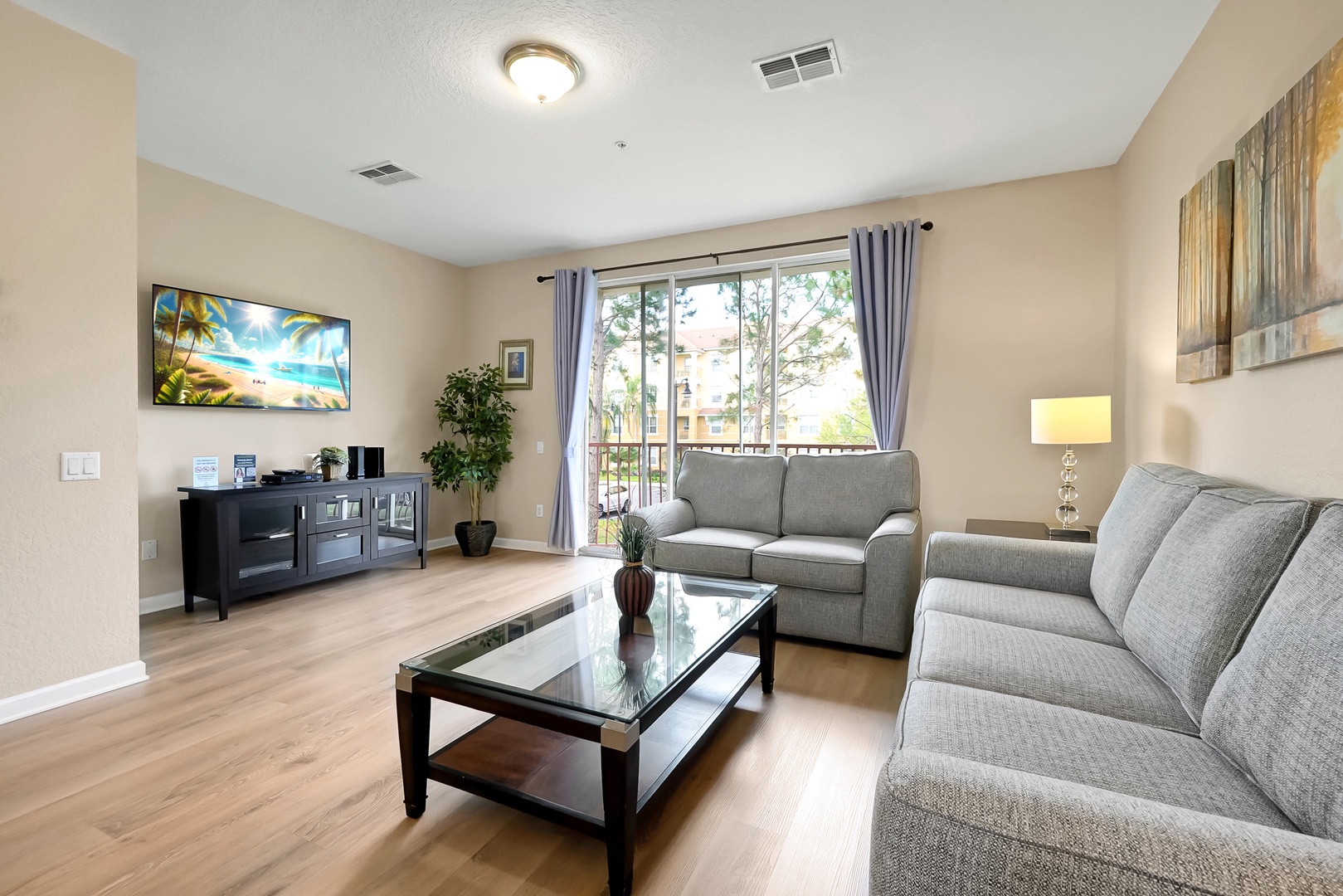 Relax in your spacious living room with plush seating, modern TV entertainment, and peaceful balcony views through elegant curtains.