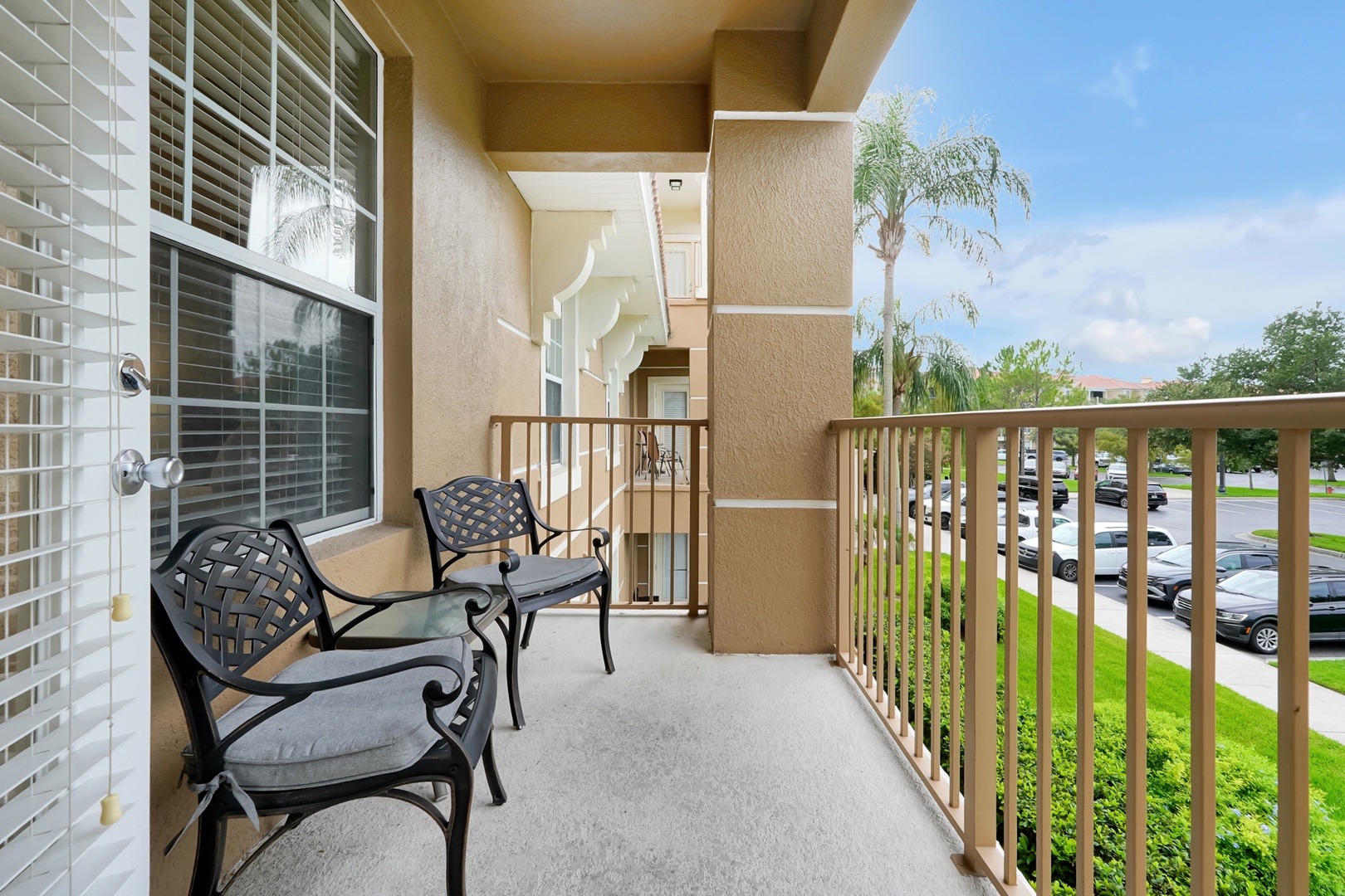 Step onto your private covered balcony with comfortable seating overlooking a peaceful neighborhood framed by swaying palms and lush greenery—your perfect spot to unwind with morning coffee or evening conversation.