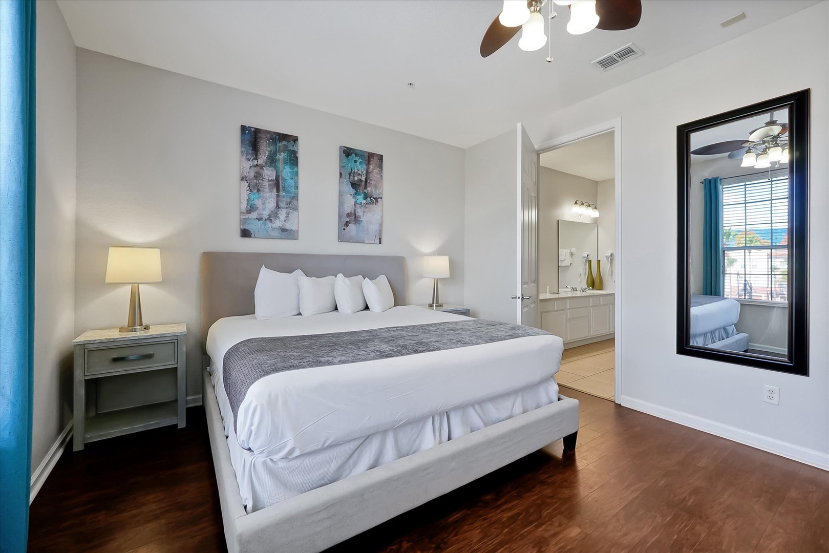 Sink into crisp white linens on your plush king bed, with warm hardwood floors underfoot and modern artwork creating a serene retreat.