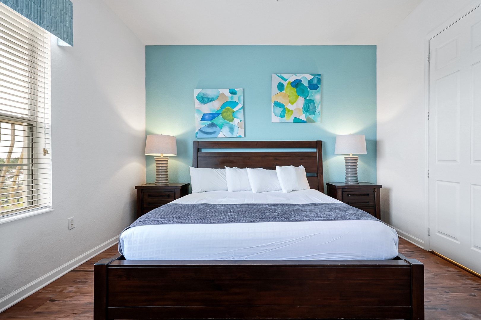 Sink into crisp white linens and let the serene turquoise accent wall wrap you in coastal calm—your perfect retreat after a day of adventure.