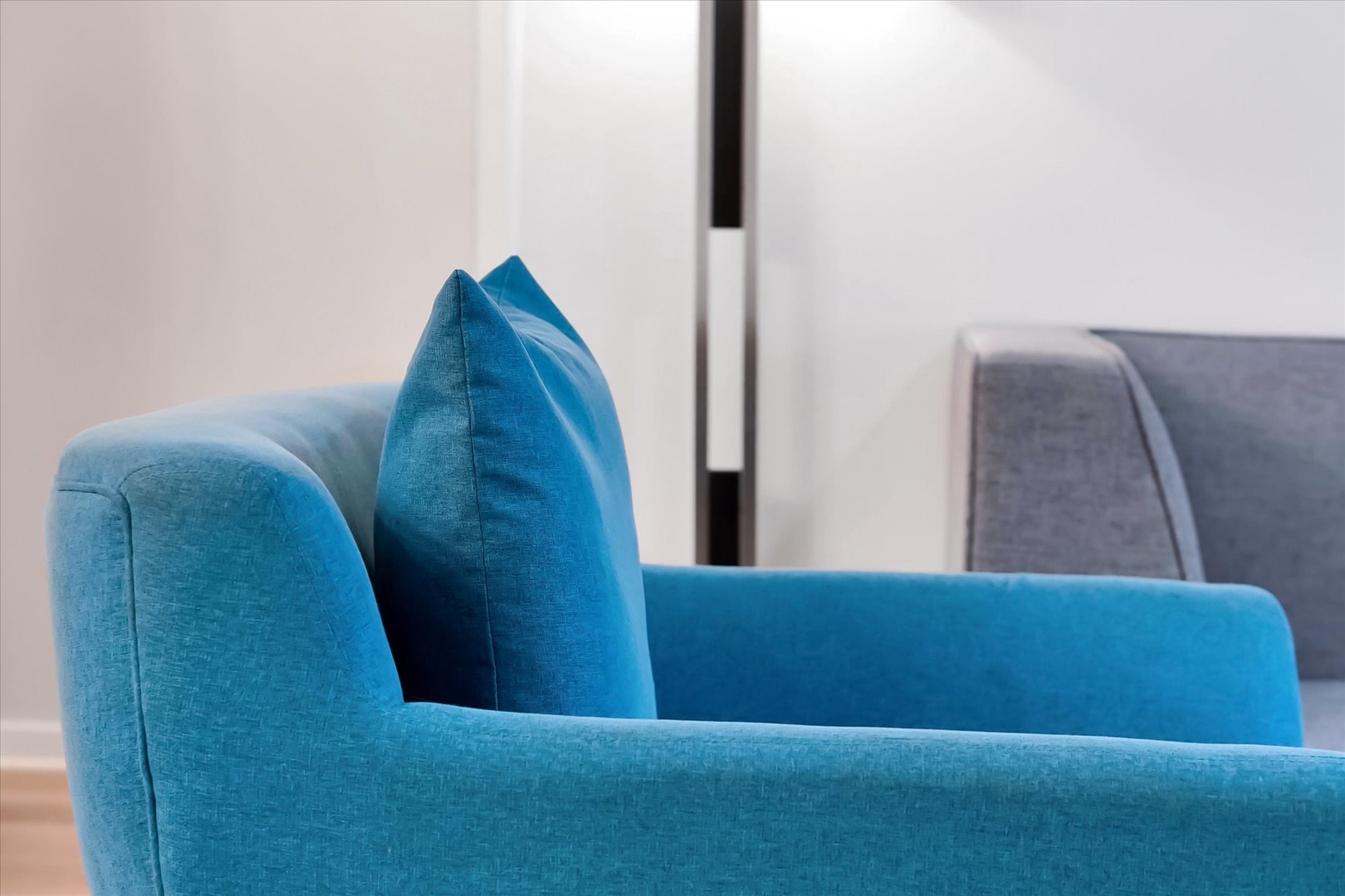 Sink into this vibrant blue armchair where plush cushions and soft fabric create your perfect reading nook.