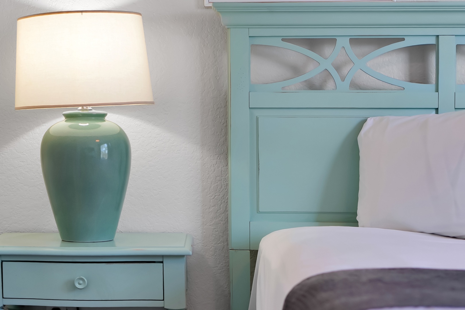 Sink into plush bedding beneath the warm glow of your elegant bedside lamp in this beautifully appointed coastal-themed bedroom.