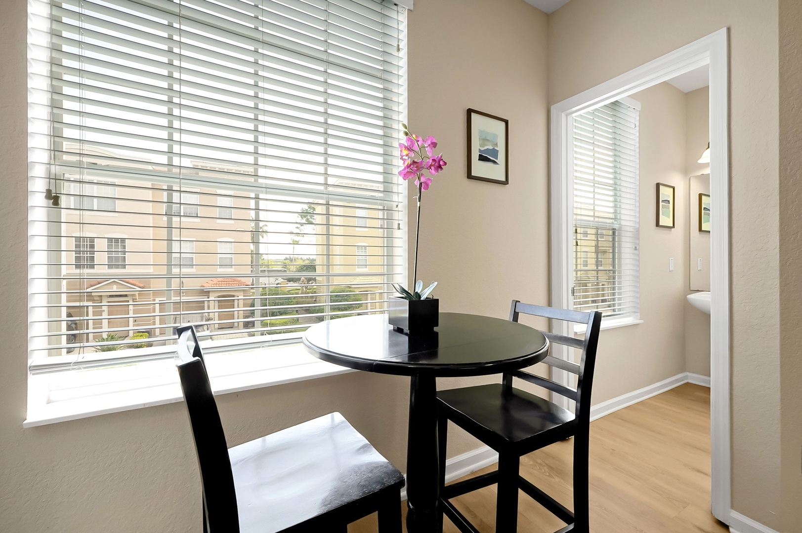 Your intimate dining corner features a sleek table for two beside bright windows, perfect for morning coffee or romantic meals.