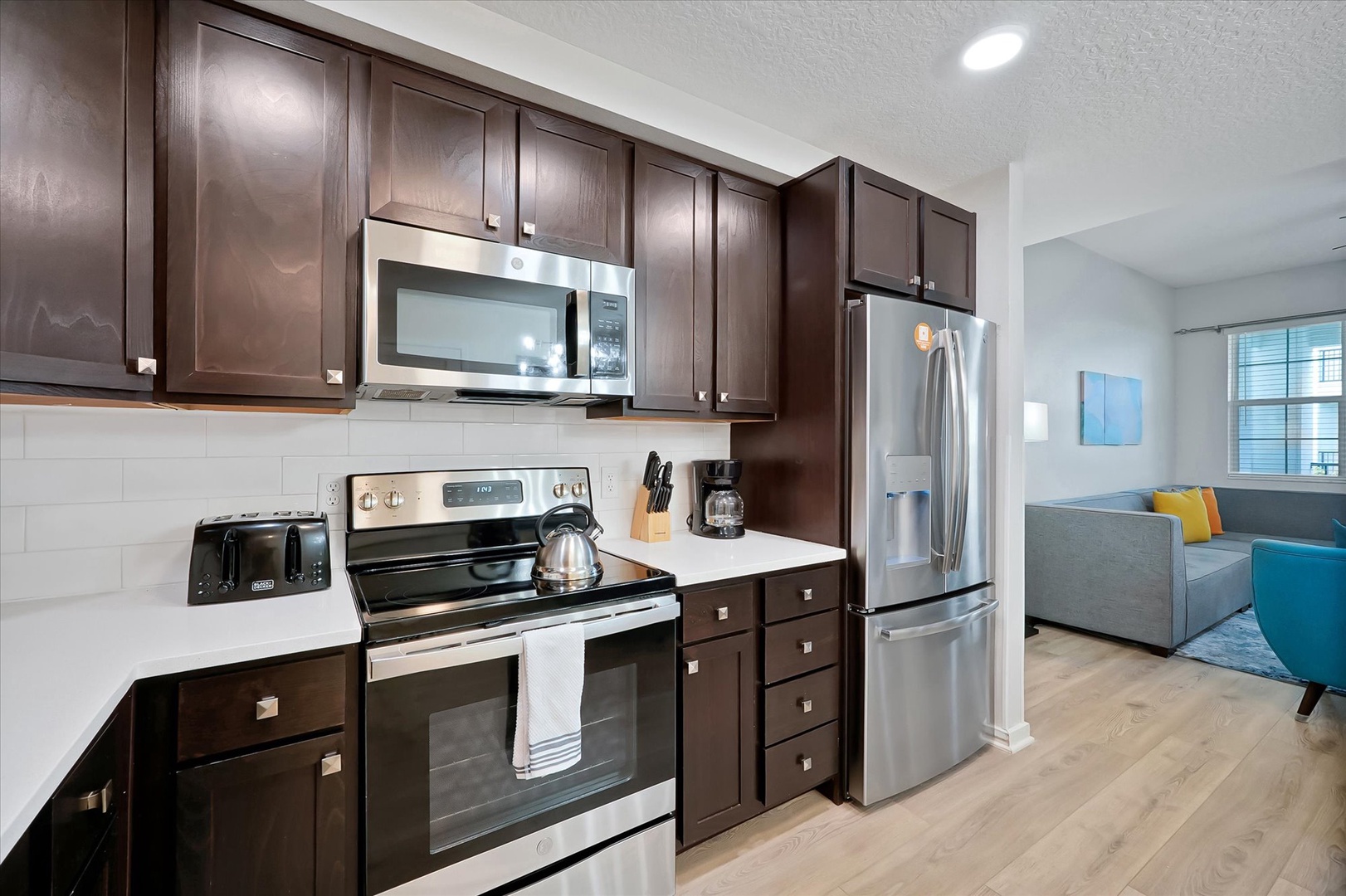Step into your stylish kitchen featuring dark wood cabinetry, stainless steel appliances, and bright countertops perfect for preparing meals.