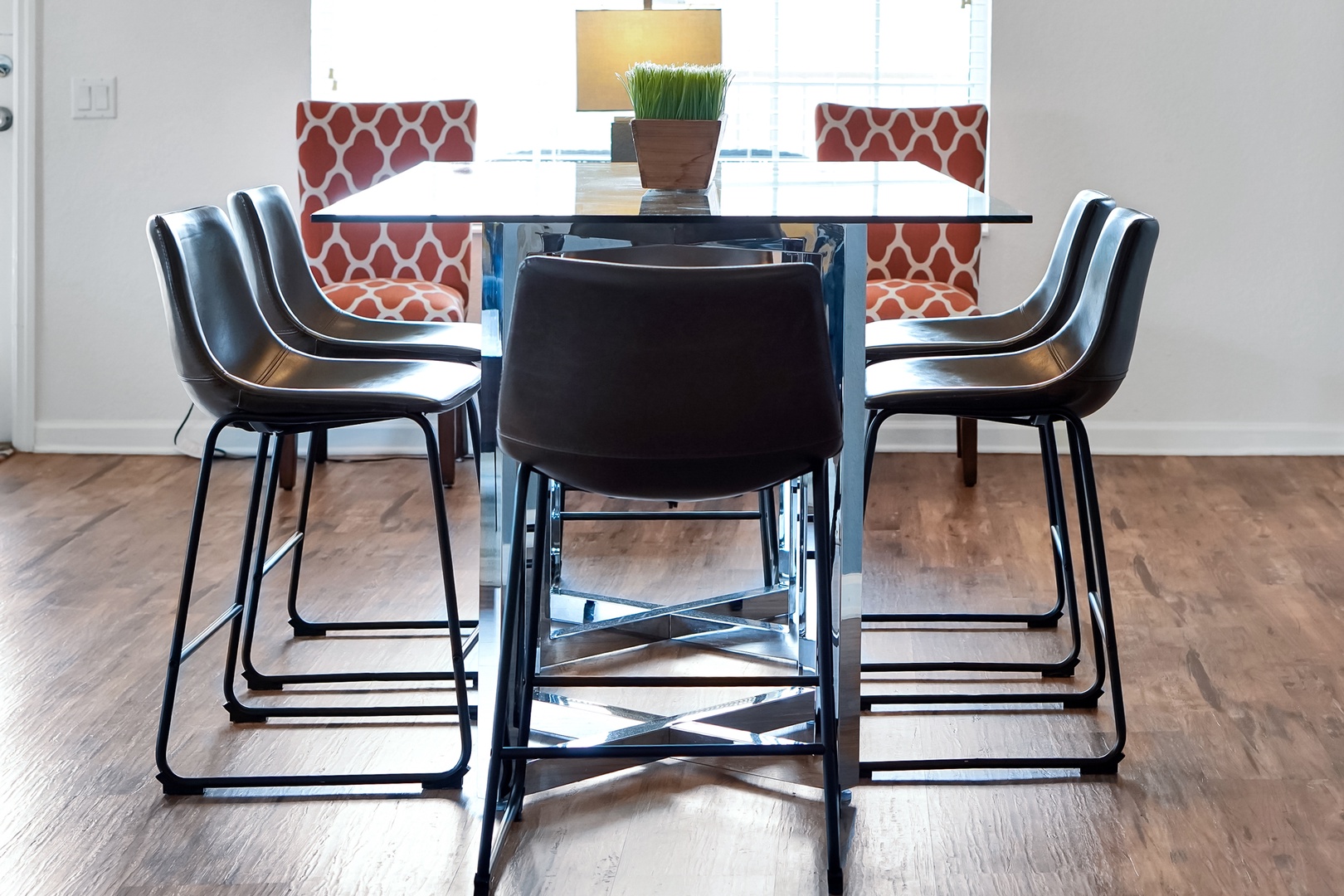 Gather around this sleek glass-topped table with modern seating—your space for morning coffee, game nights, or sharing meals together in comfort and style.