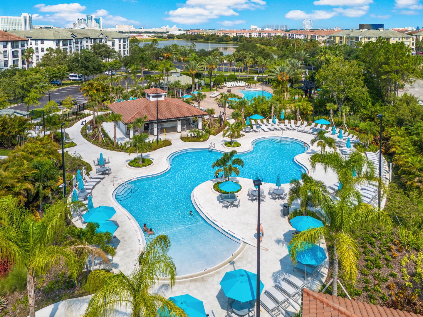 Aerial view of the resort-style pool complex featuring multiple pools, palm trees, and sunny Florida surroundings.