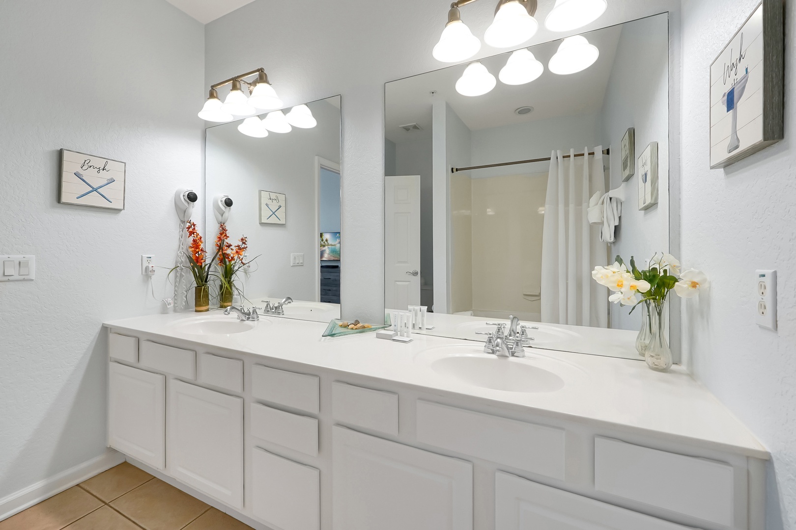 Pamper yourself in this bright, spacious bathroom with dual vanities, perfect lighting, and thoughtful touches like fresh flowers.
