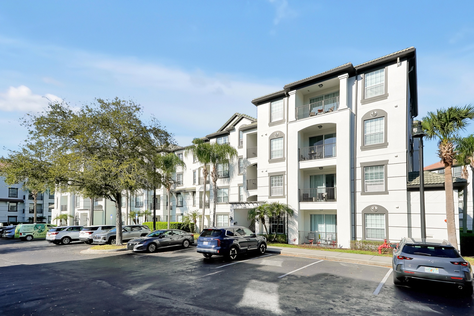 Multi-story apartment complex featuring modern architecture with palm trees and convenient parking in a sunny Florida-style setting.