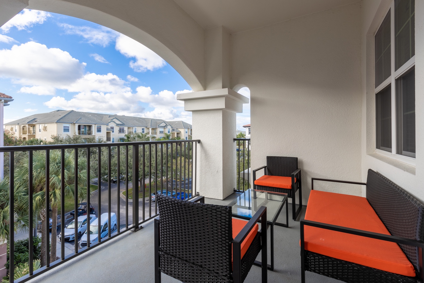 Step onto your private balcony and sink into comfortable seating with vibrant orange cushions, perfect for morning coffee or evening relaxation.