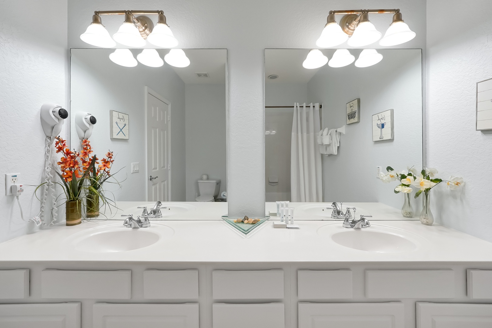 Your spa-like bathroom features dual vanities with bright lighting and fresh flowers, creating a luxurious start to each day.