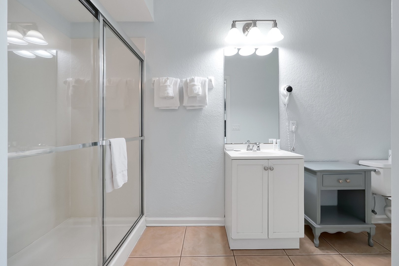 Step into your spacious full bathroom featuring a walk-in shower, vanity with storage, and thoughtful touches like fresh towels awaiting your arrival.