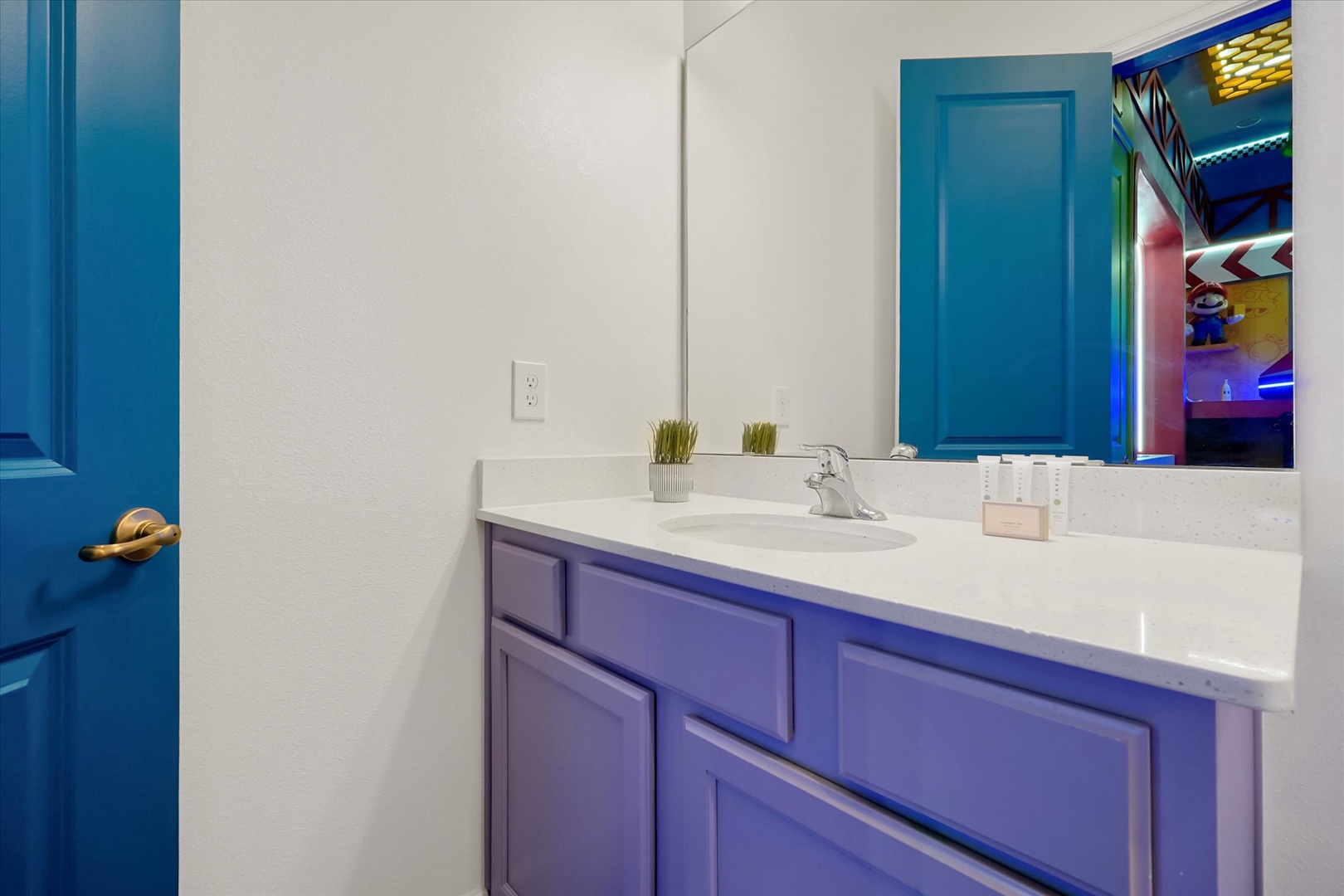 Step into your private bathroom with vibrant purple cabinetry, a sleek white countertop, and playful decor touches. The LED-lit mirror adds a modern glow to your refreshing space.