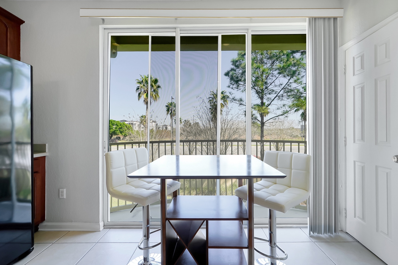 Enjoy meals with a view at your bright dining table, where floor-to-ceiling windows frame tropical palms and peaceful scenery.