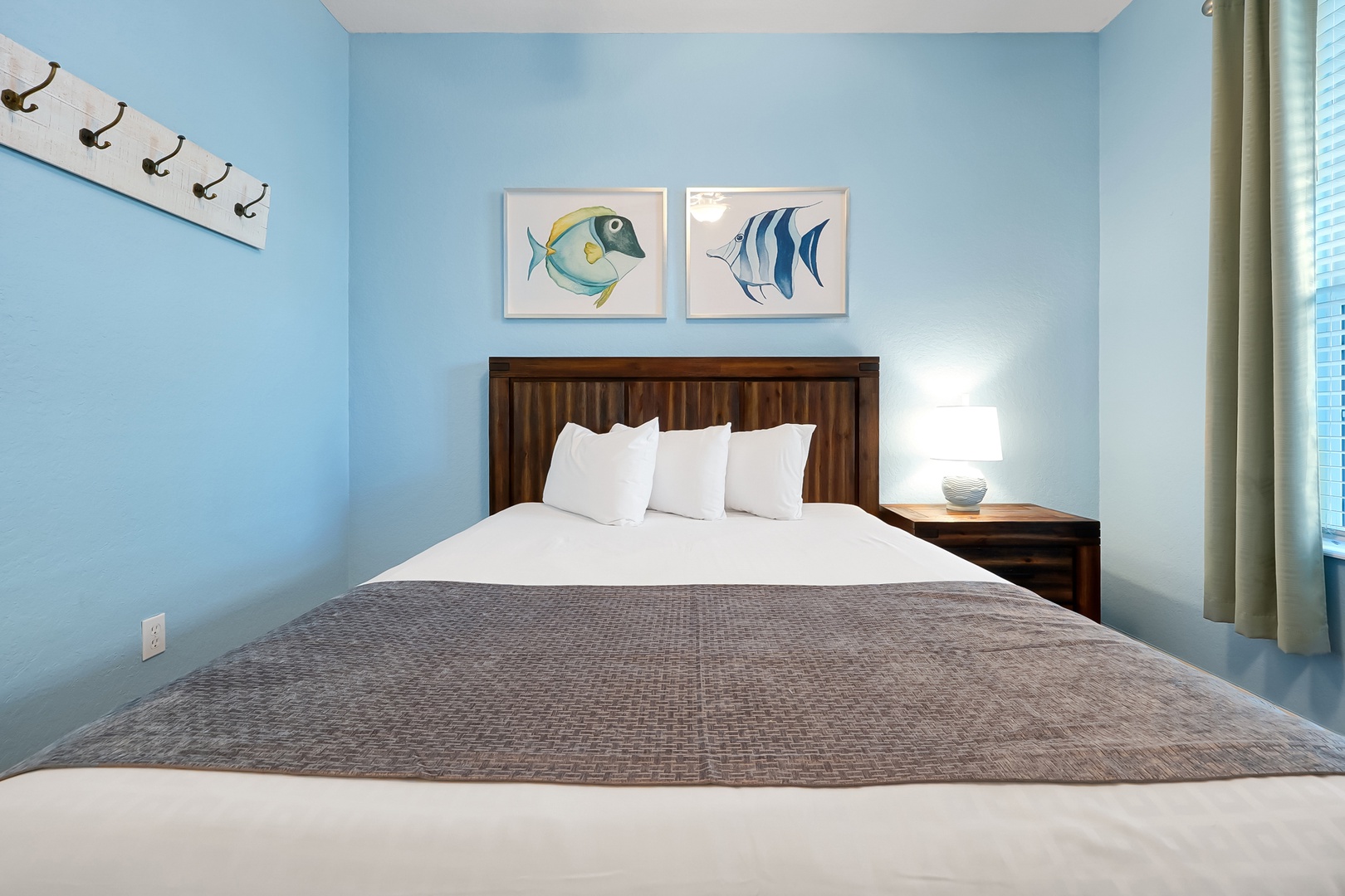 Drift off in your cozy bedroom featuring crisp linens, coastal fish artwork, and calming blue walls for peaceful nights.