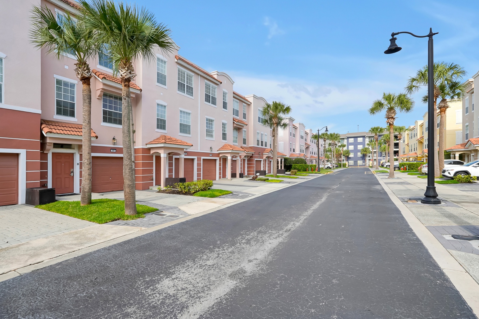 A pristine residential community featuring Mediterranean-style townhomes with red tile roofs and palm-lined streets.