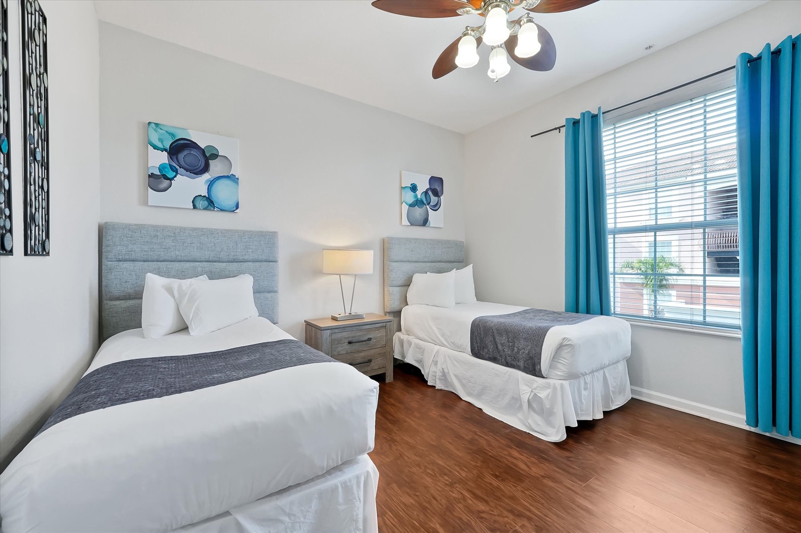 Drift off in crisp white linens while the ceiling fan gently circulates cool air through your peaceful twin bedroom retreat.