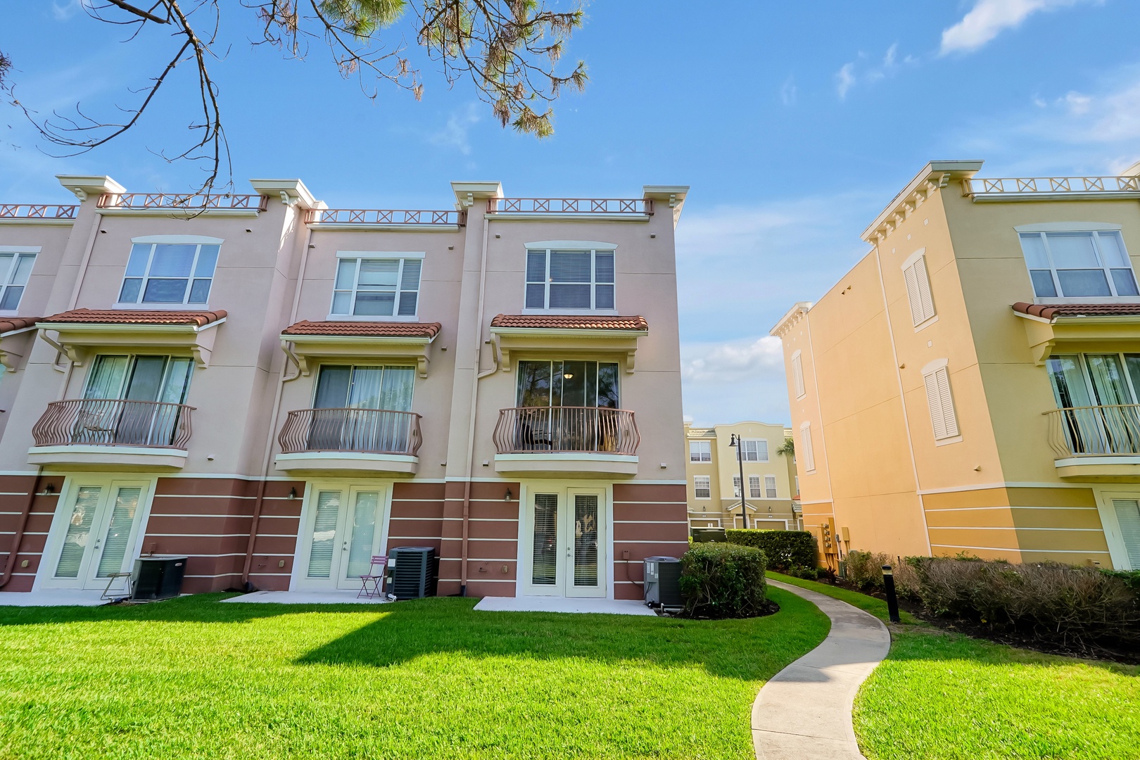 Colorful Mediterranean-style townhomes with manicured lawns and private balconies in a peaceful residential community.