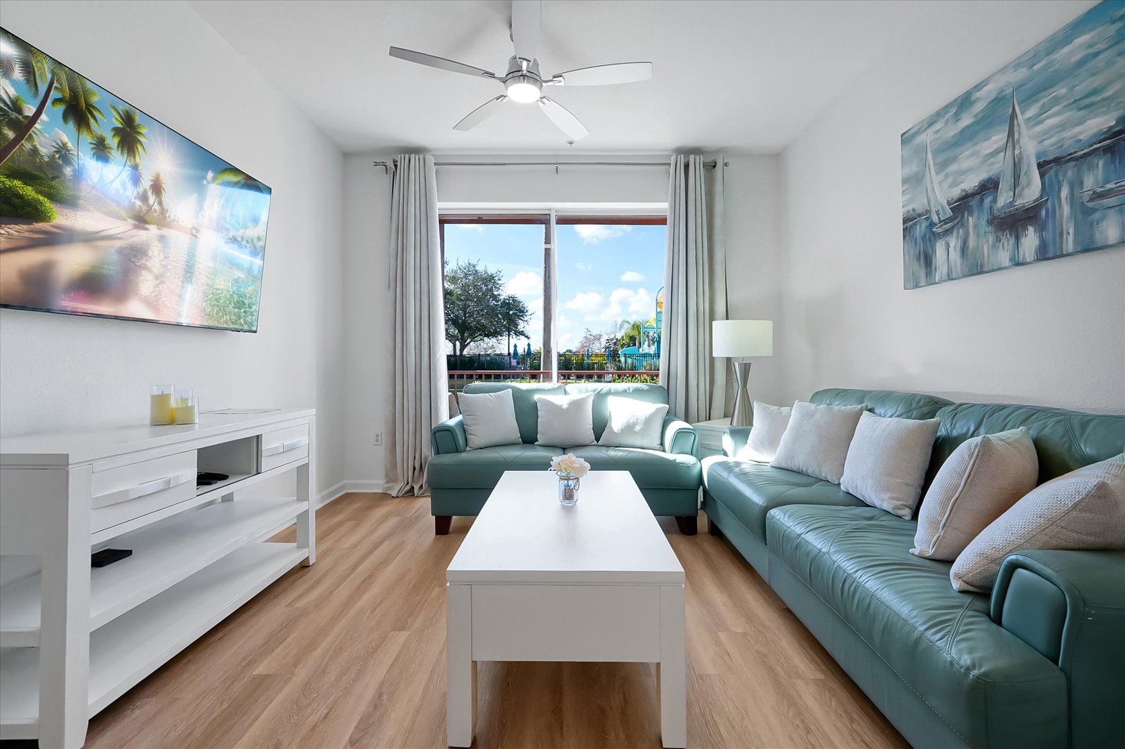 Unwind in your bright living space with plush turquoise seating, large TV, and sunny windows overlooking the vibrant neighborhood