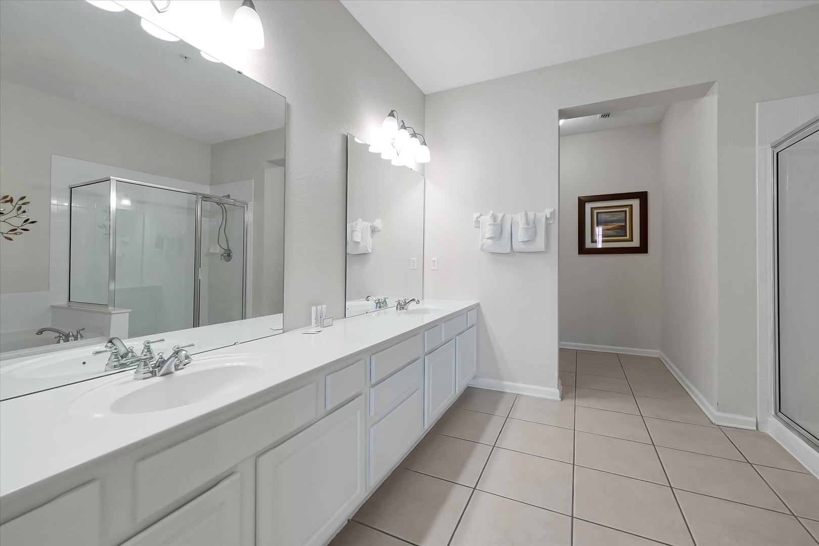 Your spacious bathroom features dual vanities, pristine white countertops, and a glass-enclosed shower for your morning routine.