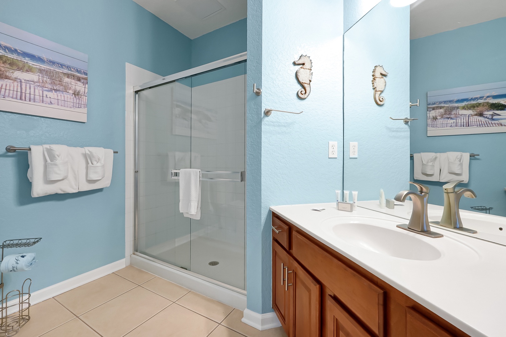 Refresh in your private coastal-themed bathroom with spacious glass shower and charming seahorse accents.