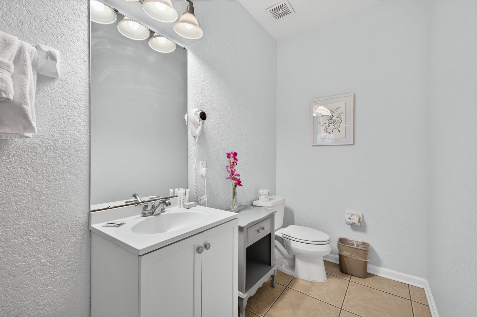 Step into your bright, spotless bathroom where fresh towels await and thoughtful touches like flowers add a welcoming feel. Everything you need is here for a refreshing start to your day.