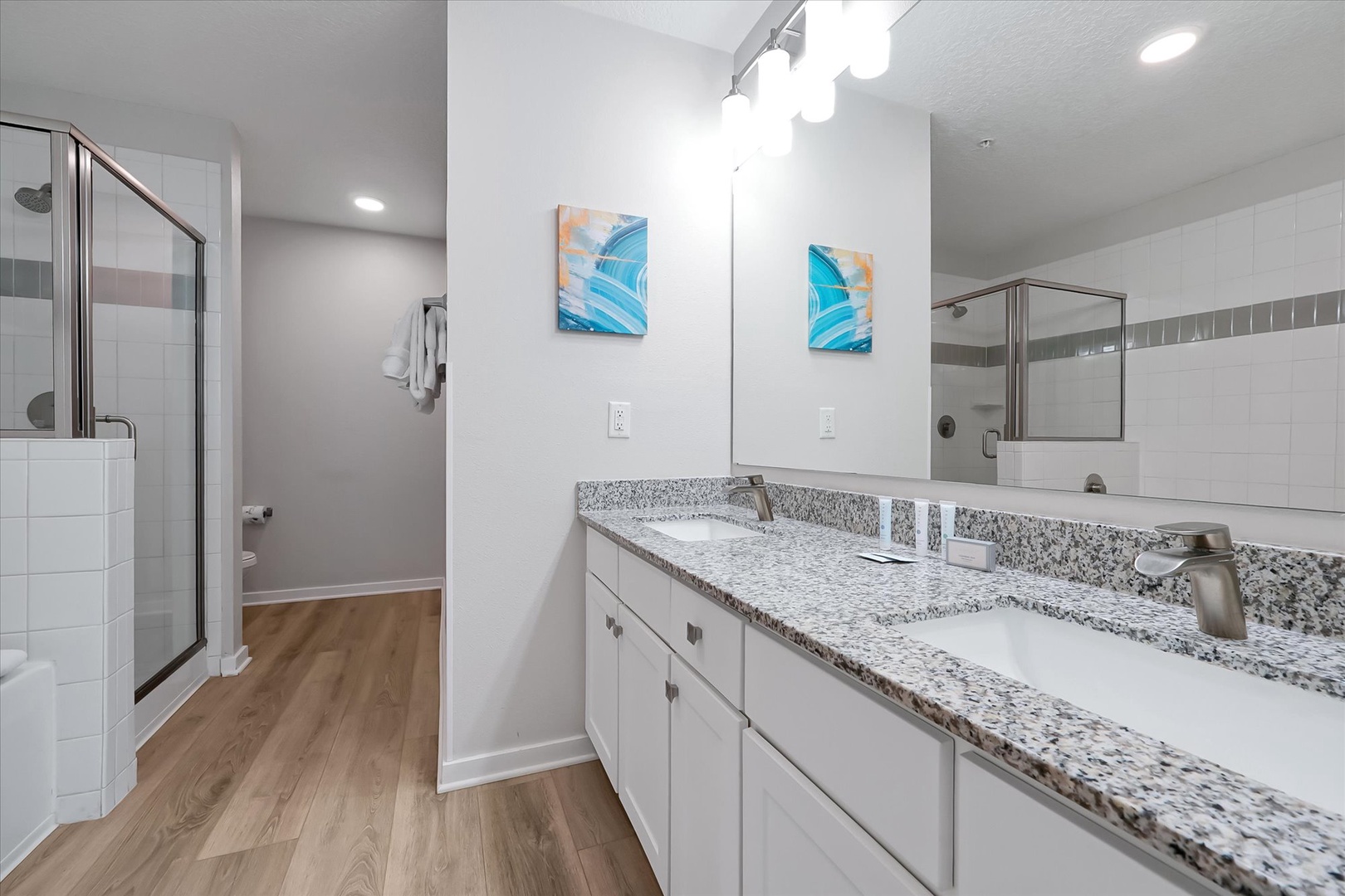 Pamper yourself in this pristine bathroom featuring dual vanities with granite countertops, glass-enclosed shower, and stylish modern fixtures.