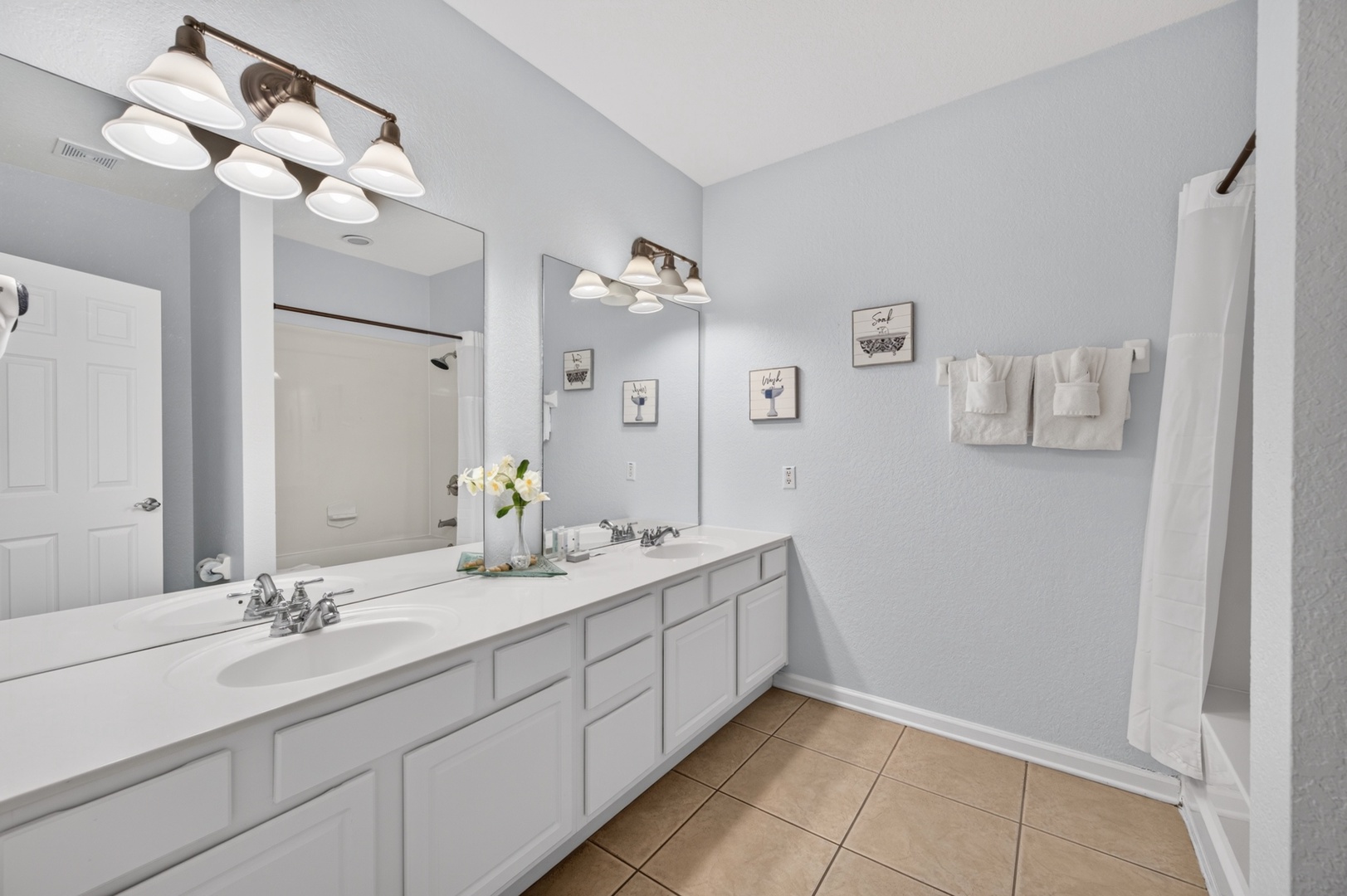 Freshen up in this spacious bathroom with double sinks, bright vanity lighting, and crisp white towels ready for your stay.