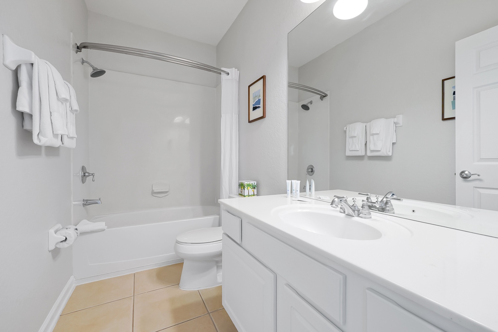 Your private bathroom features a spacious bathtub-shower combo, gleaming white countertops, and fresh towels ready for your arrival.