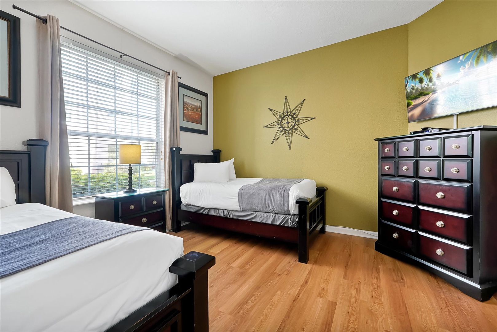Rest peacefully in this bright bedroom with twin beds, warm hardwood floors, and cheerful yellow accent wall that creates your perfect retreat.