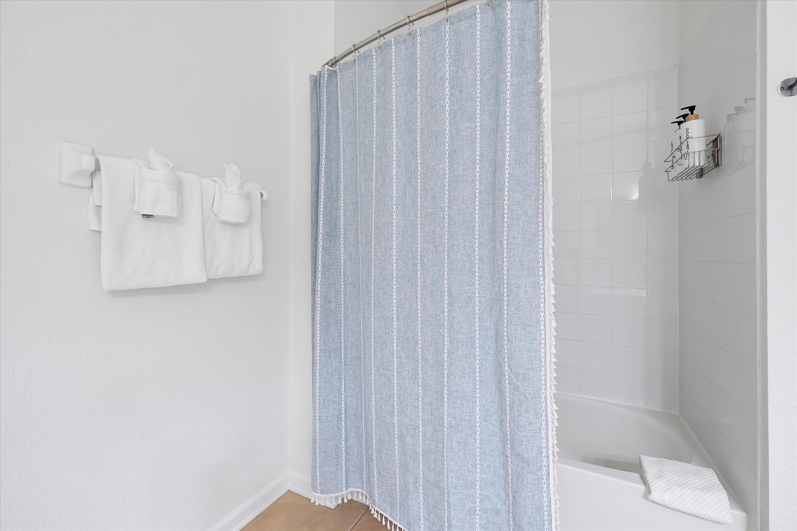 Refresh in your private bathroom with crisp white tiles, fresh towels, and a curved rod shower for comfortable bathing.