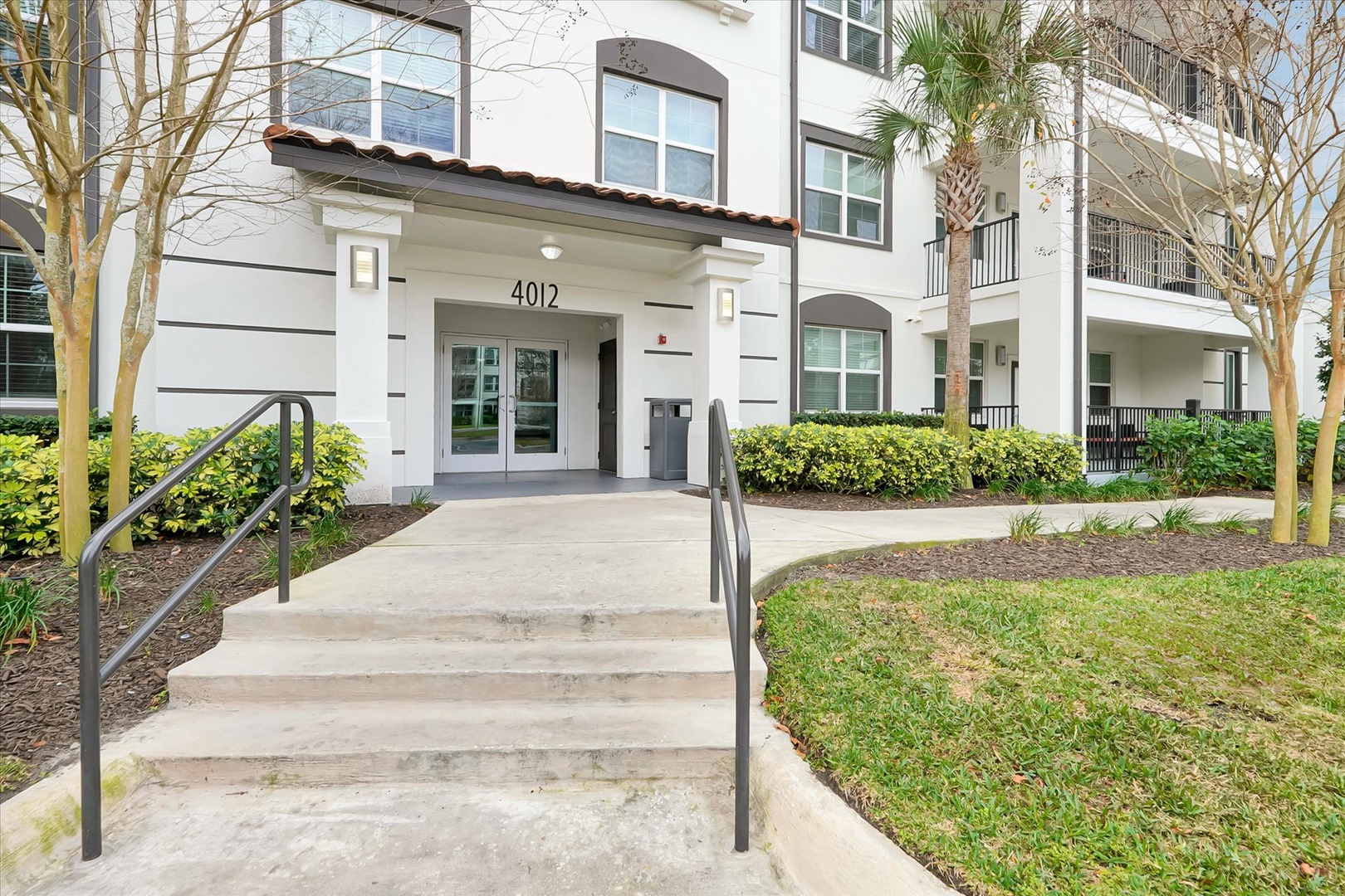 Modern apartment building entrance with well-maintained landscaping and convenient access to your comfortable stay.
