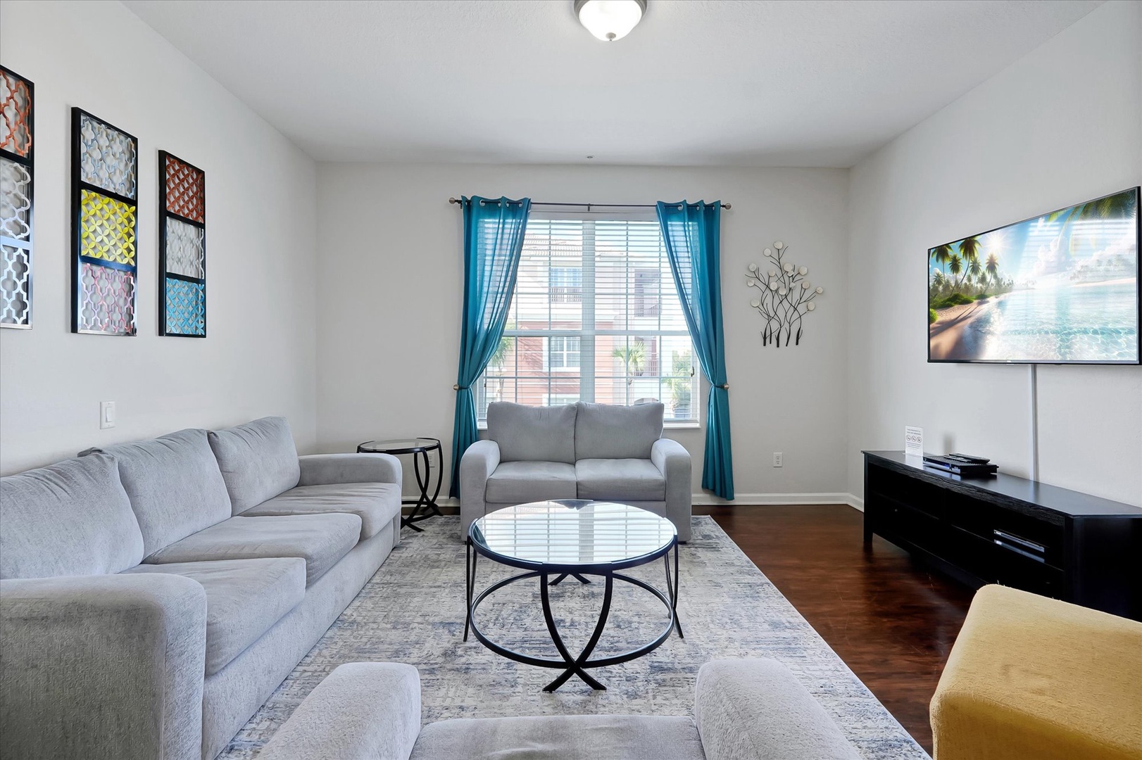 Relax in your stylish living room featuring plush seating, vibrant artwork, and a large TV for cozy entertainment.