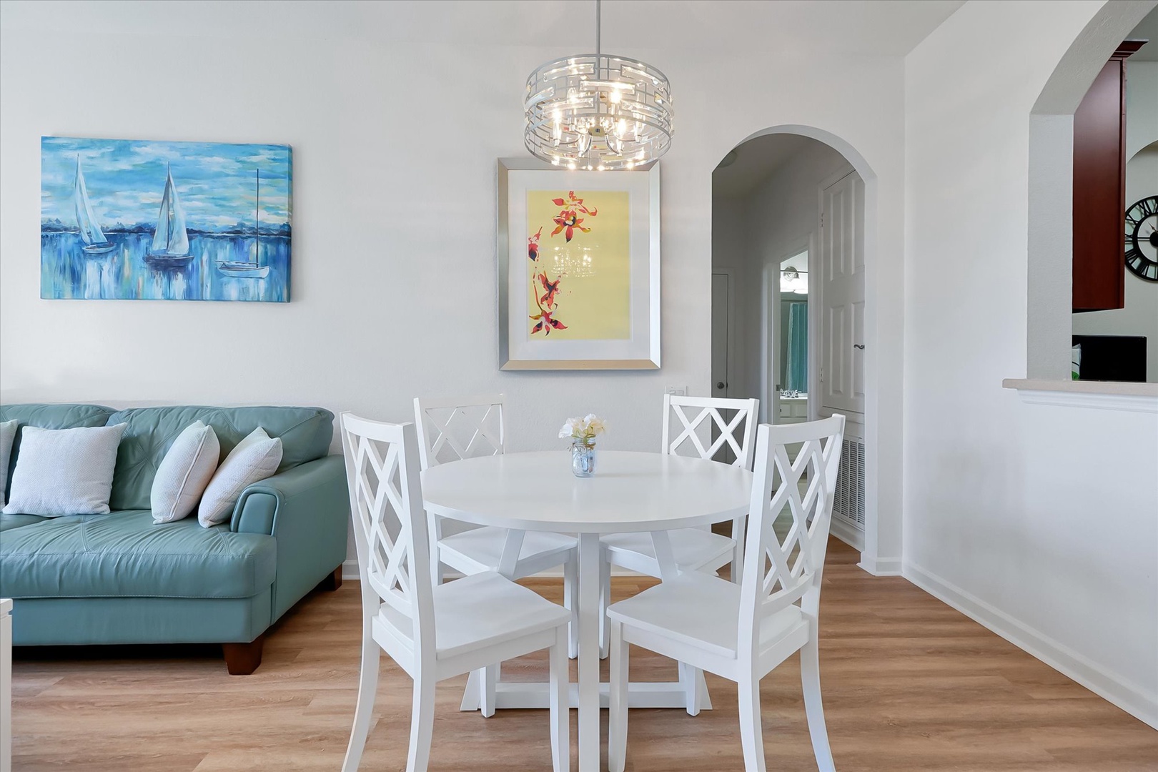 Gather around your bright dining table beneath elegant pendant lighting, with coastal artwork creating a serene backdrop for memorable meals.