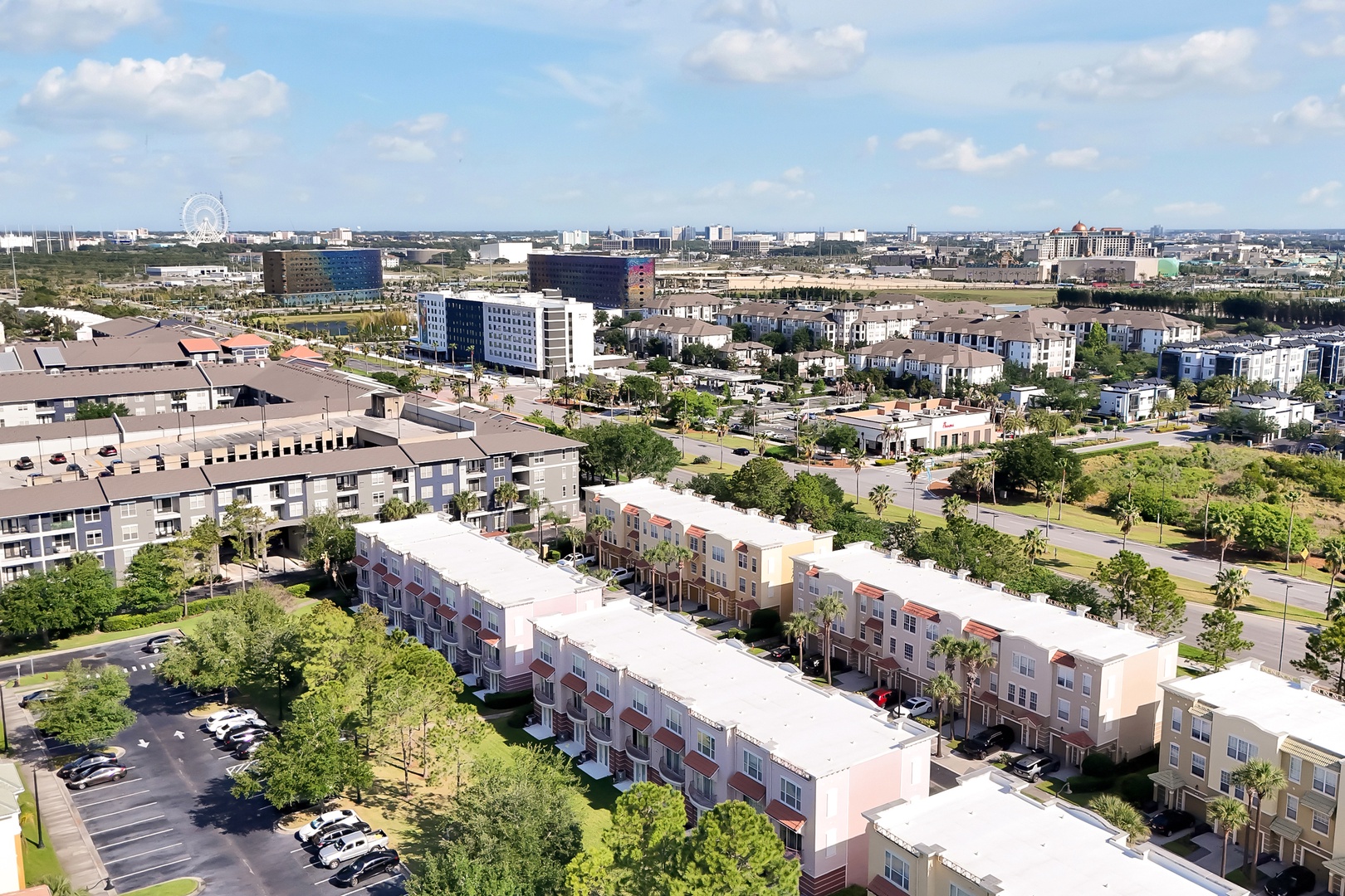 Aerial view of a vibrant mixed-use development featuring modern residential buildings, office complexes, and green spaces in an urban setting.