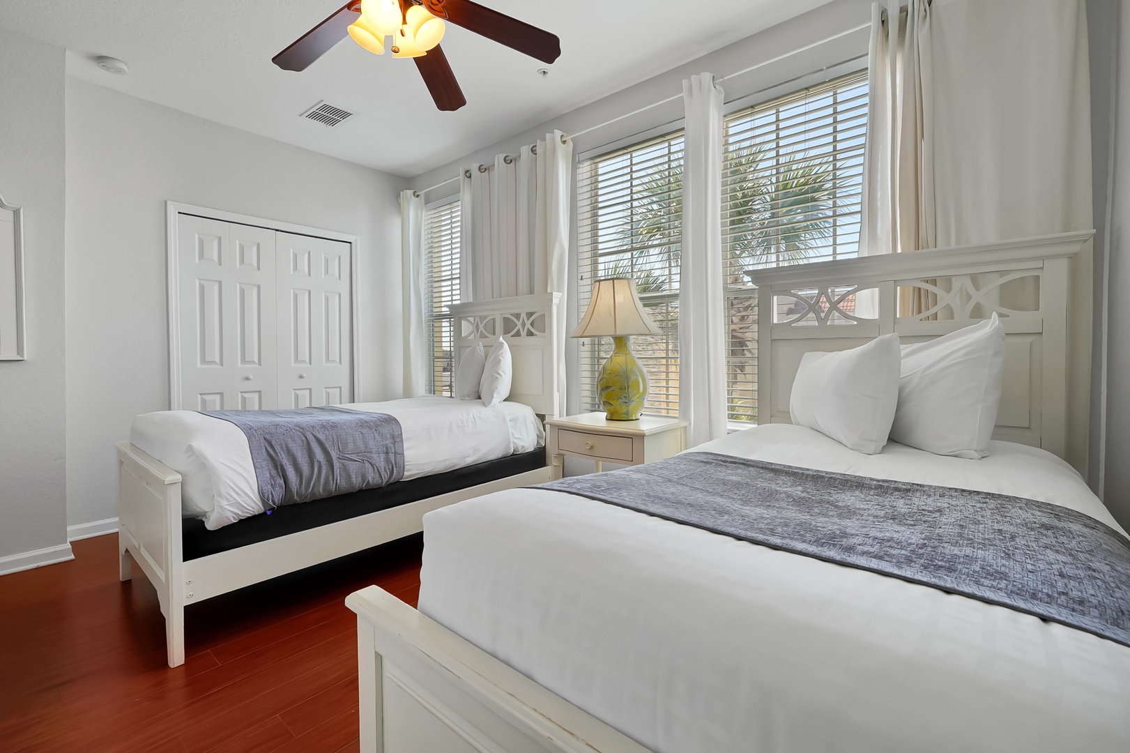 Rest peacefully in your bright twin bedroom featuring crisp white linens and gentle natural light streaming through plantation shutters.