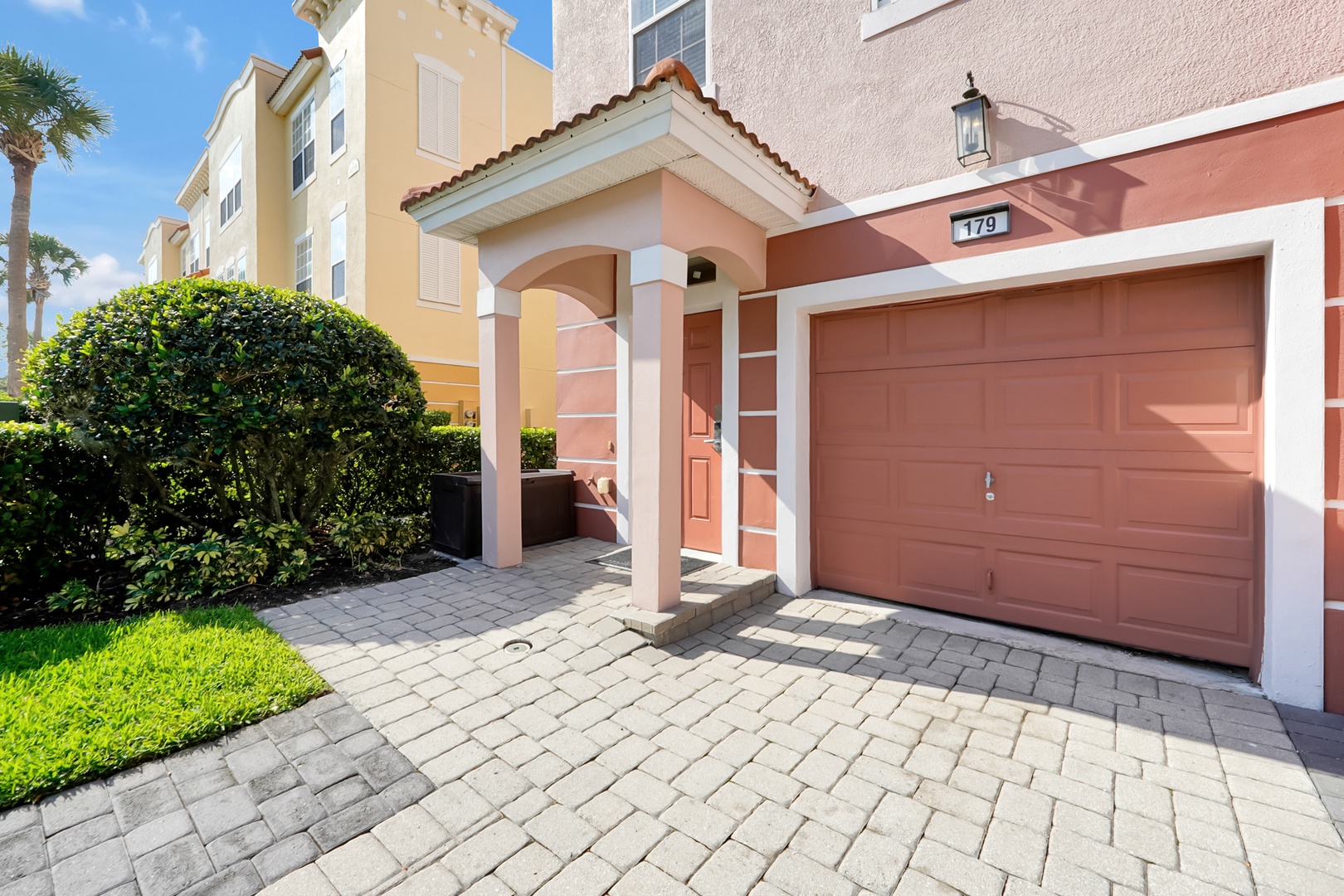 Welcoming entrance with covered porch and private garage, nestled in a vibrant resort community with tropical landscaping.