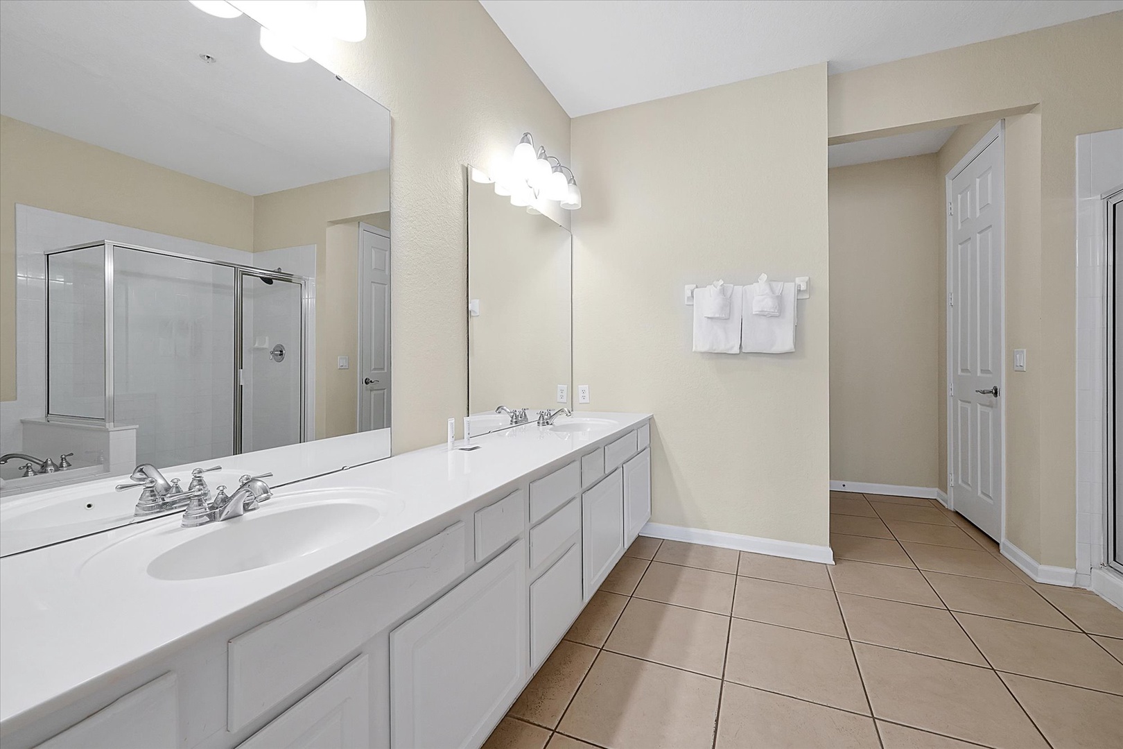 Your spacious bathroom features dual vanities and a separate glass shower, with fresh towels ready for your stay.