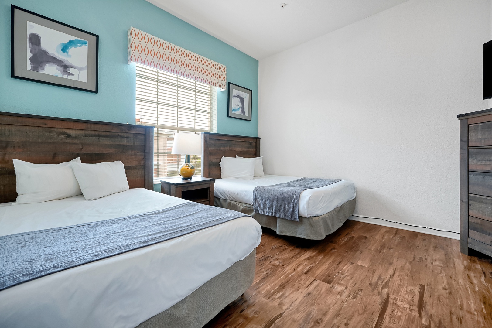Sink into crisp linens and modern comfort in this bright bedroom with warm wood accents and a cheerful pop of turquoise that makes unwinding feel effortless.