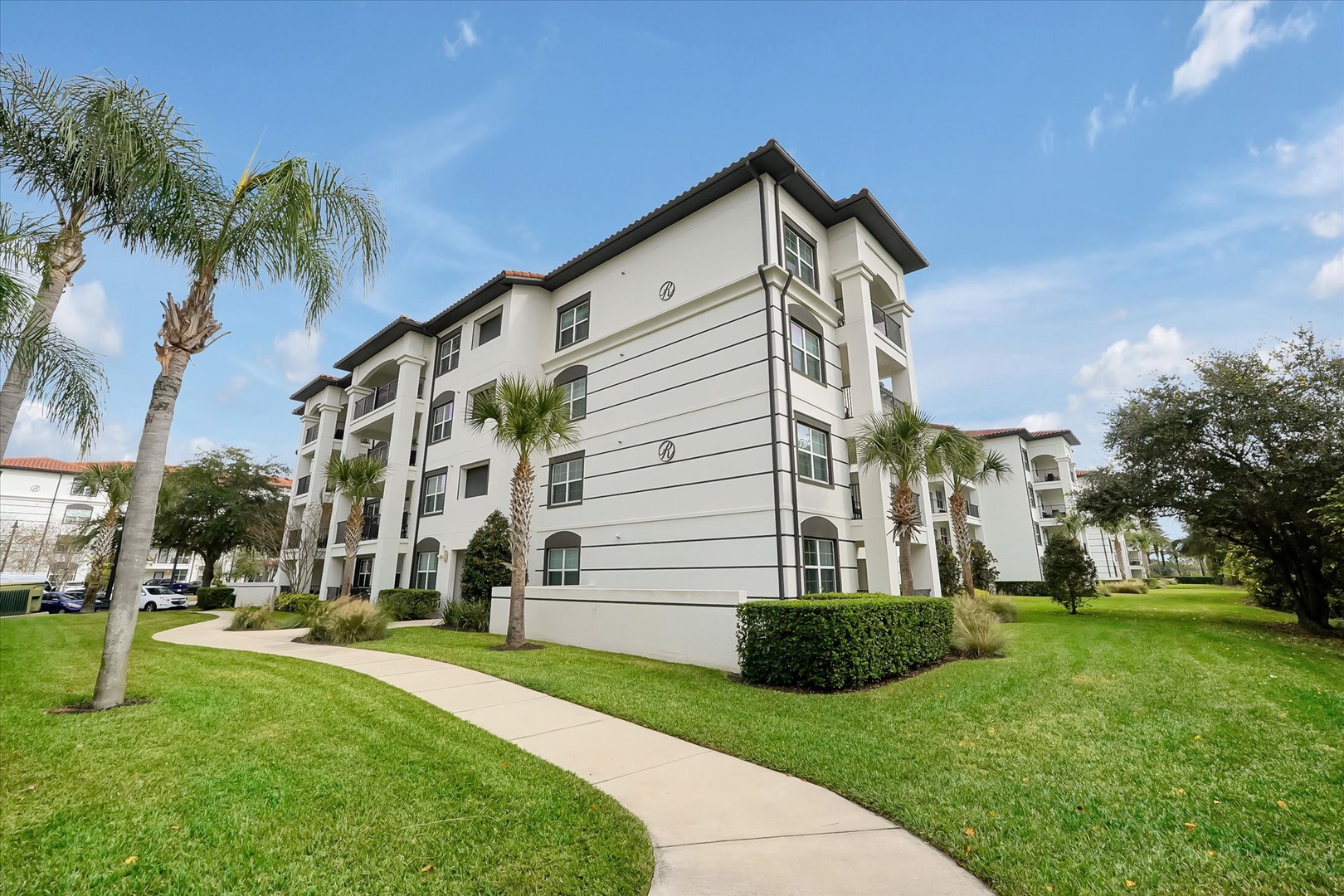 Multi-story vacation rental buildings set amid tropical landscaping with palm trees and manicured lawns.