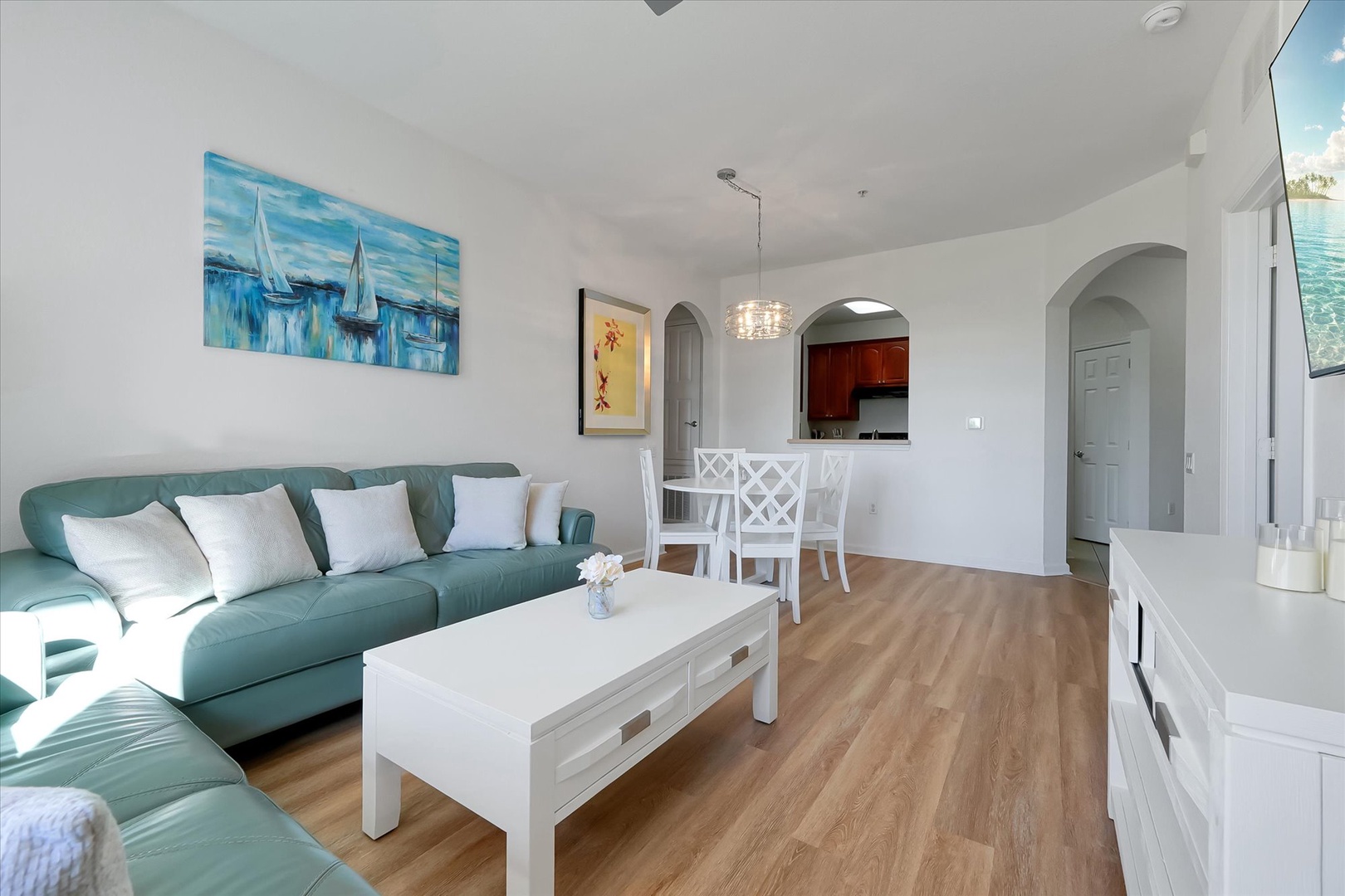 Relax in your bright, open-plan living space featuring coastal artwork, plush sectional seating, and elegant dining area perfect for your getaway.